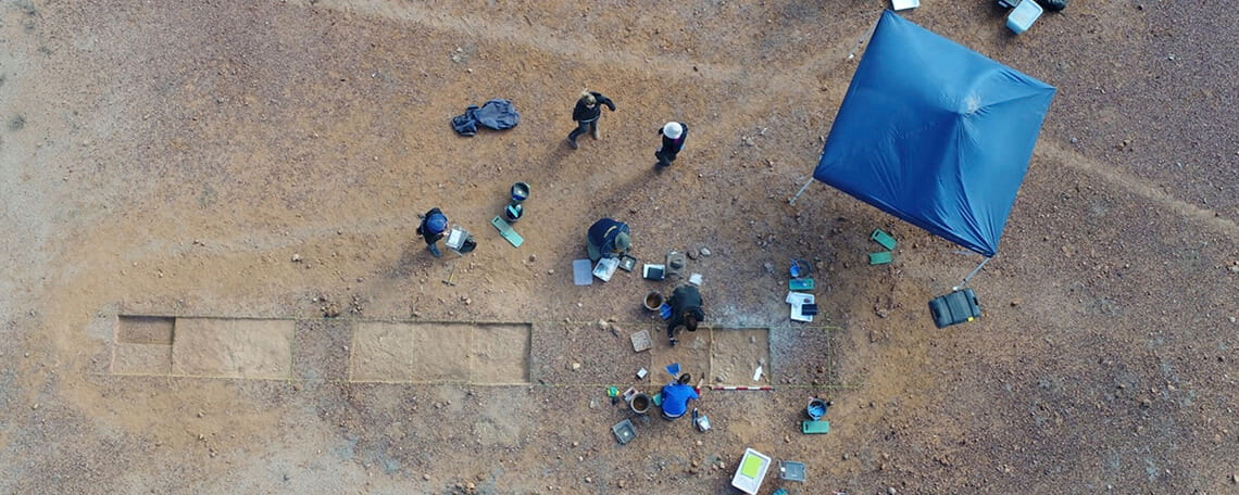 Aerial view of an archaeological excavation site with workers and equipment.