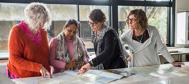 Four female USQ lecturers looking at map of Aboriginal land areas