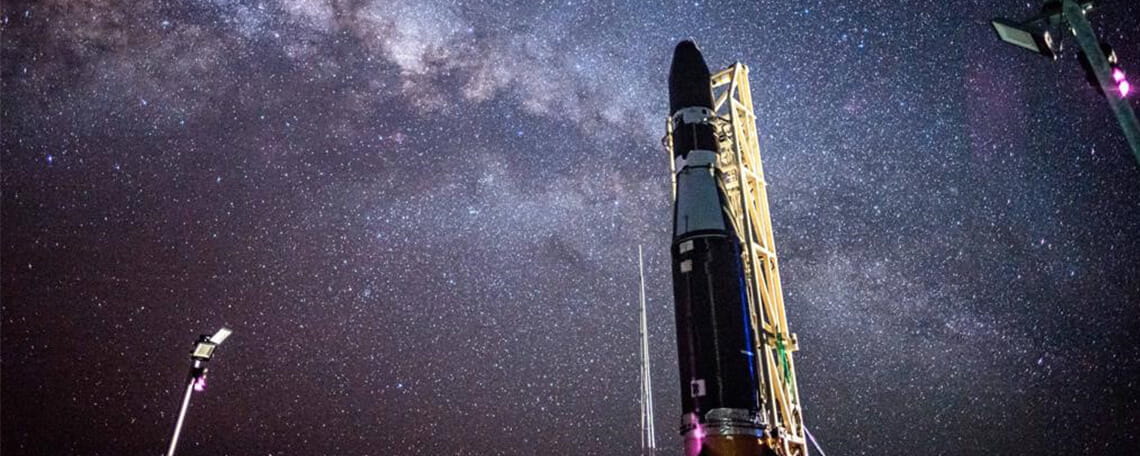 A rocket poised for launch against a backdrop of the starry night sky.