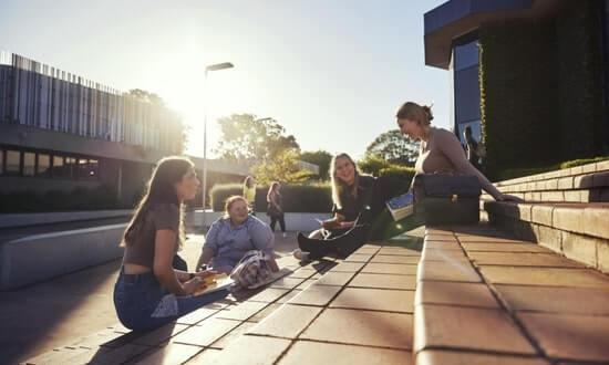 Group of students enjoying a sunny day on campus steps.
